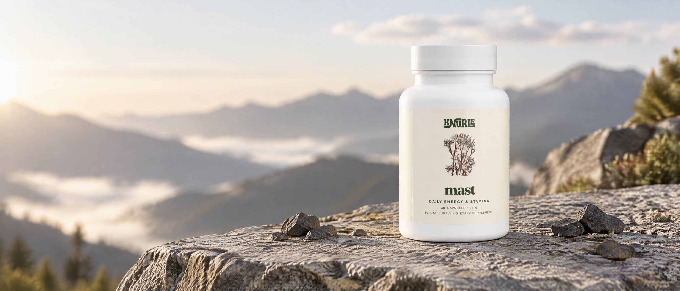 A bottle of Mast standing on a slab of mountain rock with hills in the morning haze behind it