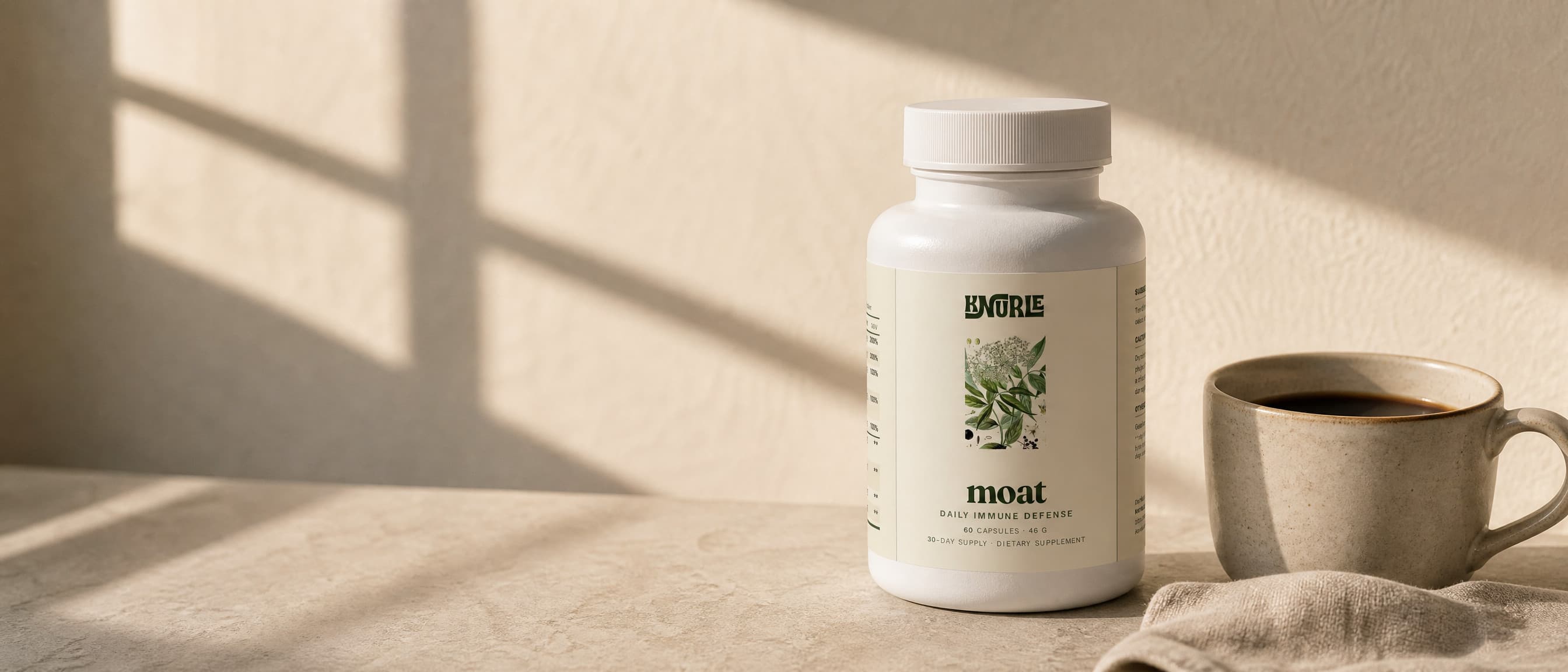 A bottle of Moat on a kitchen counter beside a cup of coffee in morning light