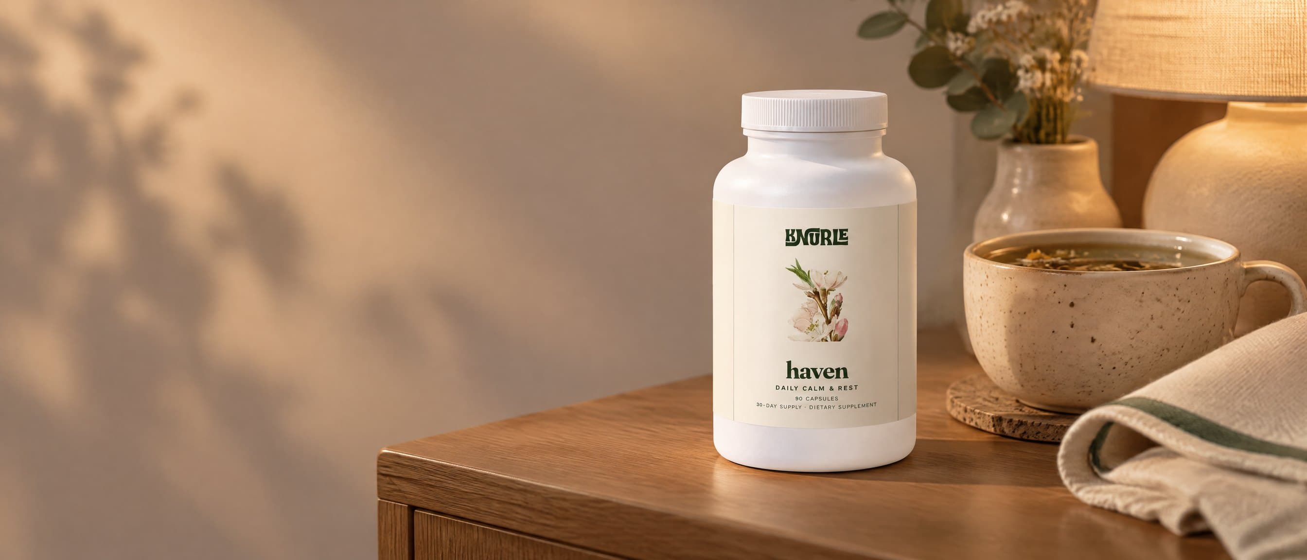 A bottle of Haven on a bedside table beside a cup of herbal tea in warm evening light