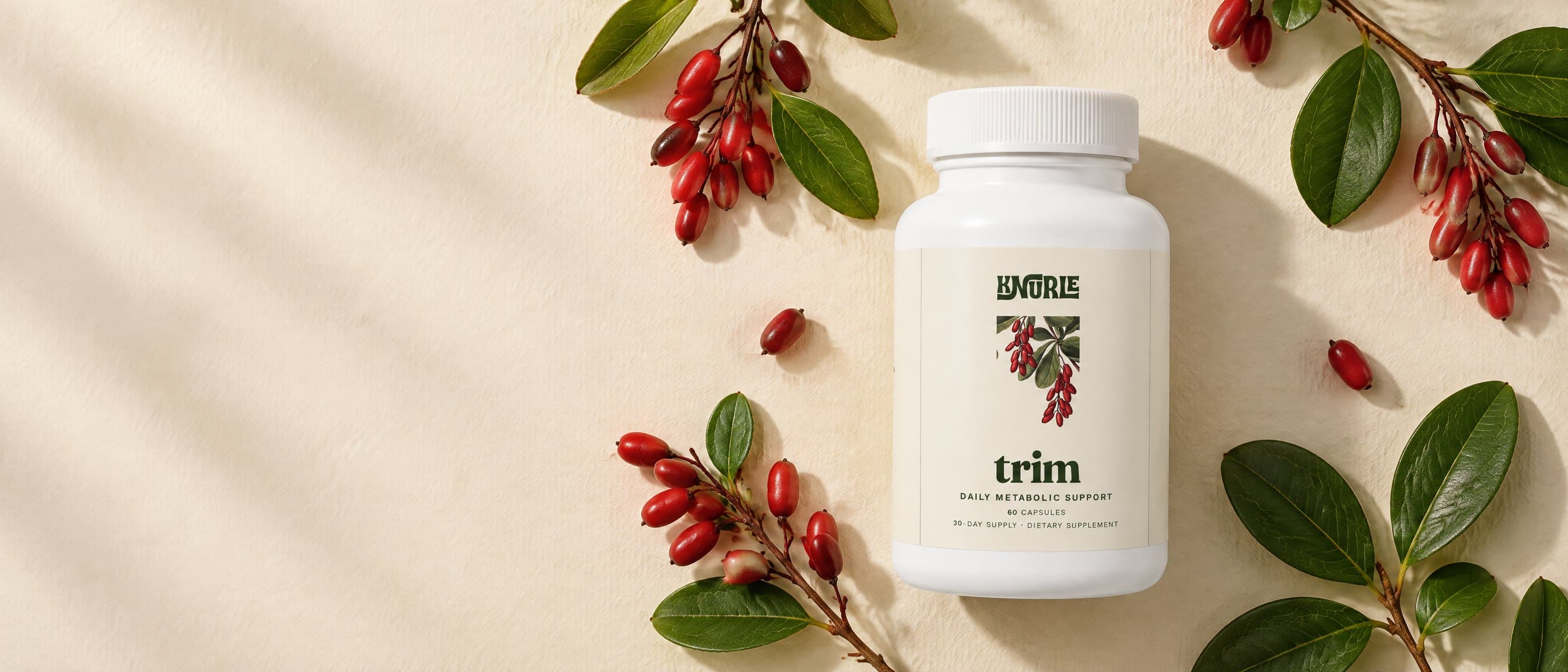 A bottle of Trim photographed from above among sprigs of red barberries and green leaves